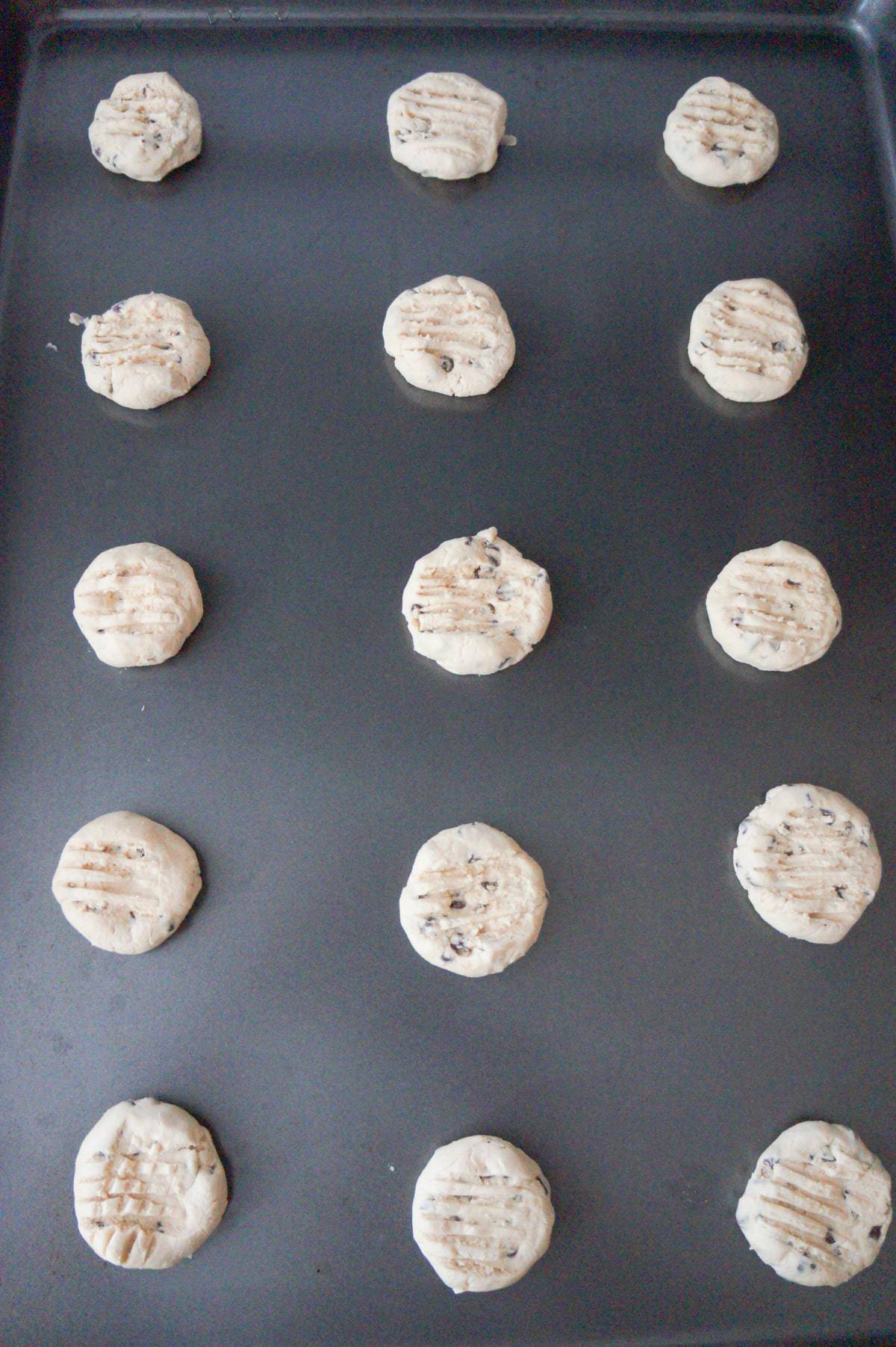 flattened shorbread cookie dough balls on a baking sheet