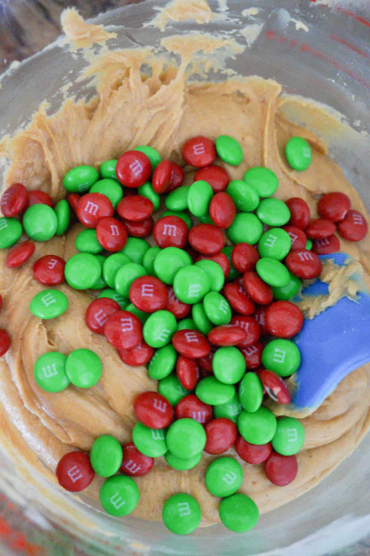 red and green M&M's on top of creamy peanut butter mixture in a bowl