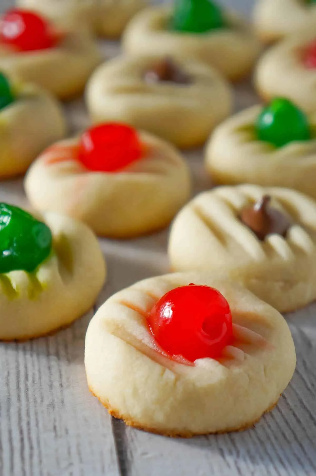 Whipped Christmas Shortbread Cookies are a buttery holiday cookie recipe that can be topped with maraschino cherries and Hershey's mini kisses.