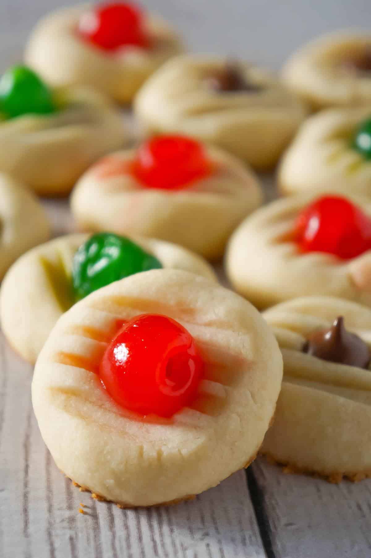 Whipped Christmas Shortbread Cookies are a buttery holiday cookie recipe that can be topped with maraschino cherries and Hershey's mini kisses.