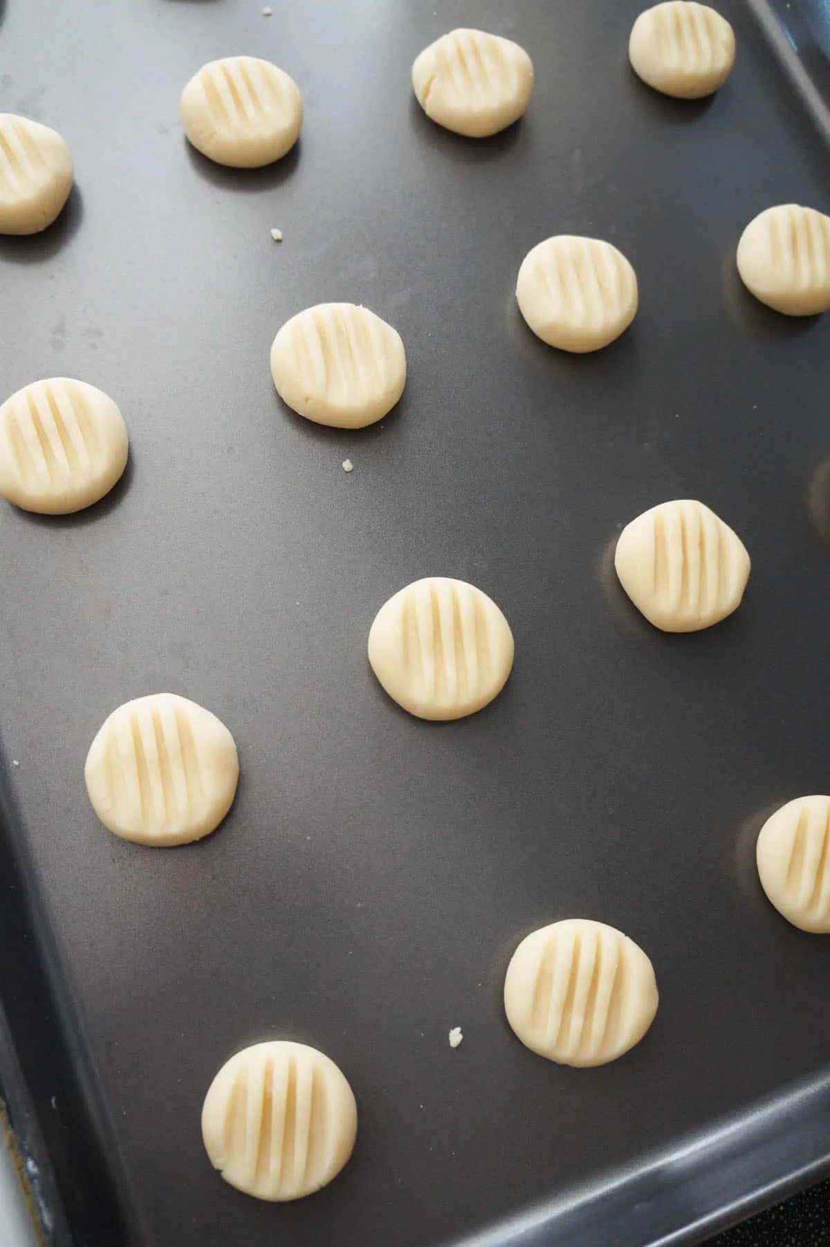 whipped shortbread cookies flattened with a fork on a baking sheet