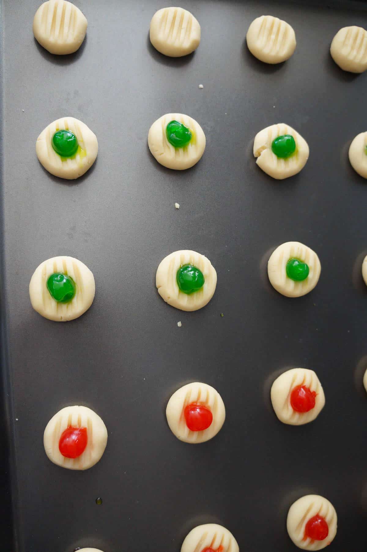 red and green maraschino cherries on top of whipped shortbread cookies before baking