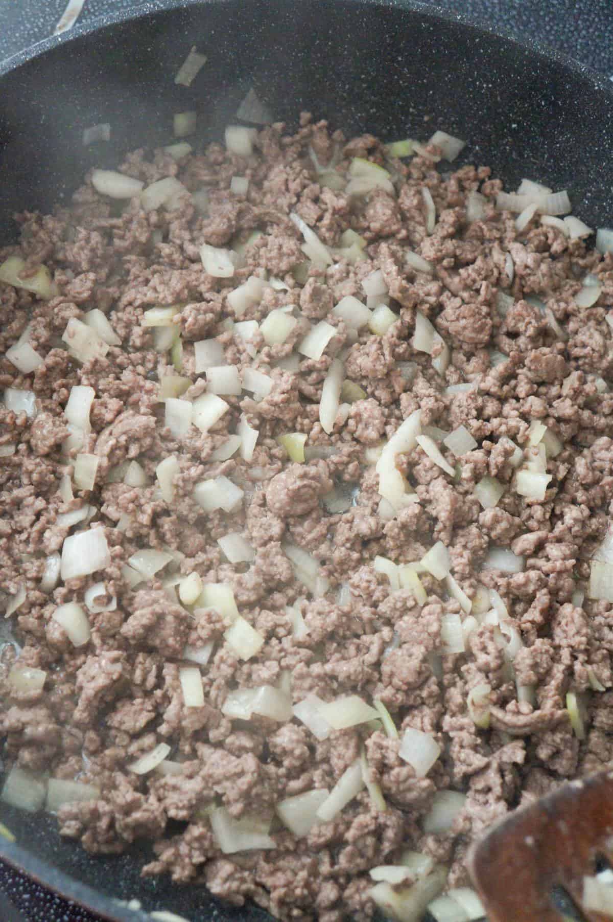 cooked ground beef and onions in a pan