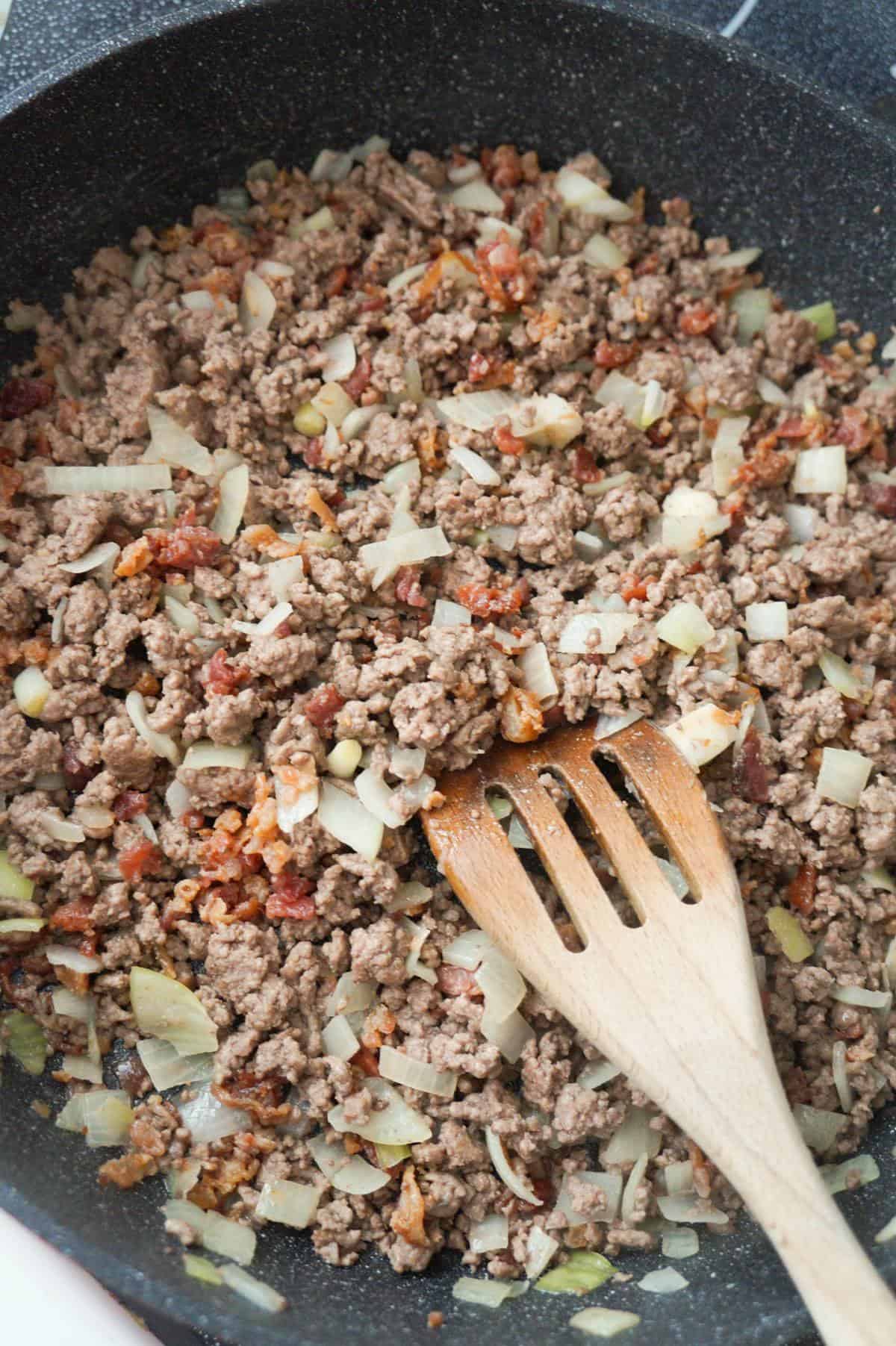 cooked ground beef, onions and crumbled bacon in a pan