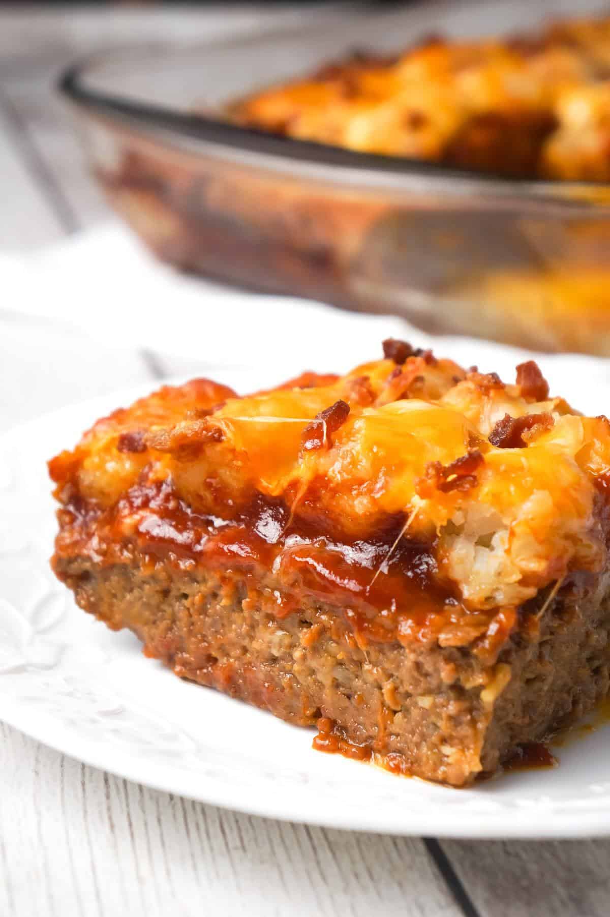 Cheesy Tater Tot Meatloaf Casserole is an easy ground beef dinner recipe with a meatloaf base, topped with a ketchup and bbq sauce glaze, tater tots, shredded cheese and crumbled bacon.