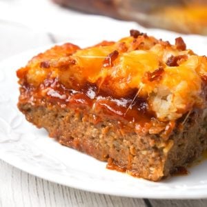 Cheesy Tater Tot Meatloaf Casserole is an easy ground beef dinner recipe with a meatloaf base, topped with a ketchup and bbq sauce glaze, tater tots, shredded cheese and crumbled bacon.