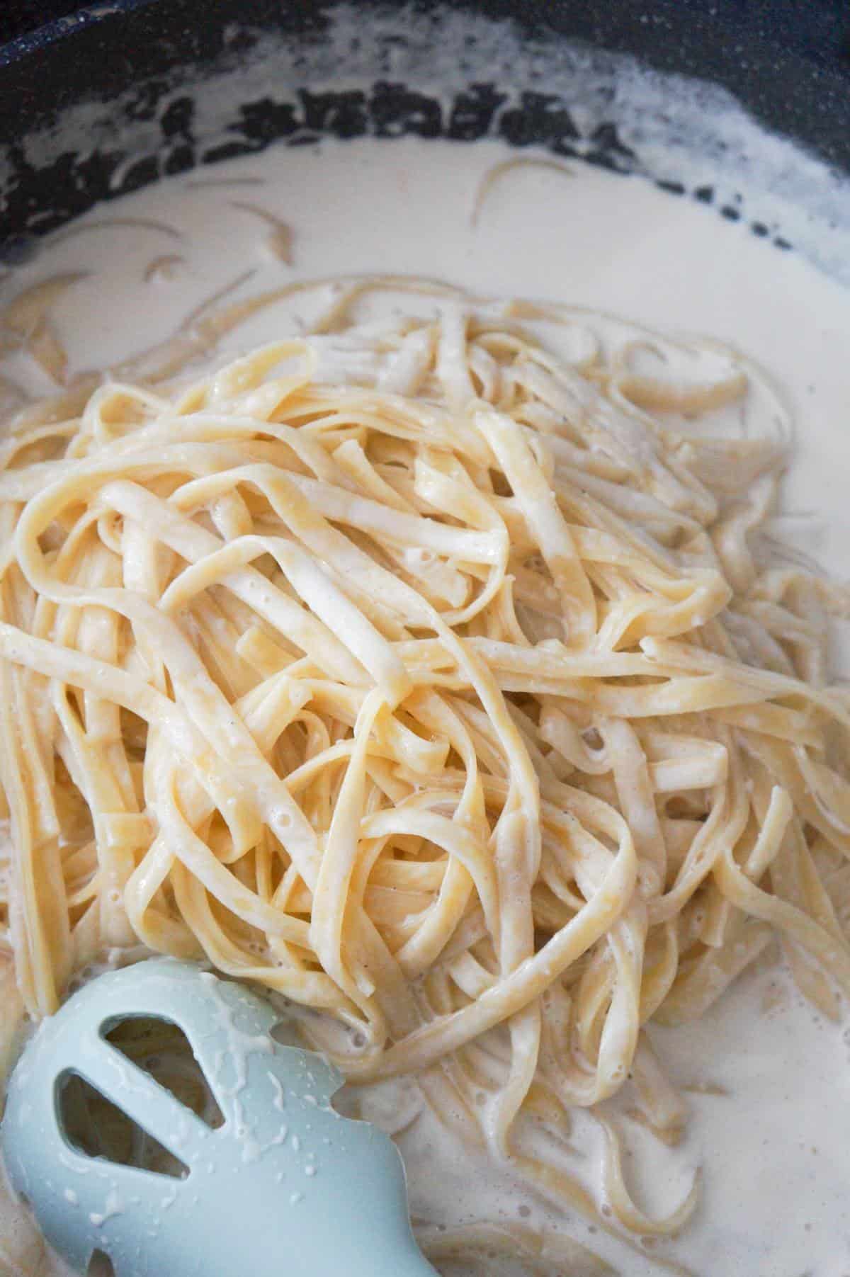 cooked fettuccine in a pan with cream sauce