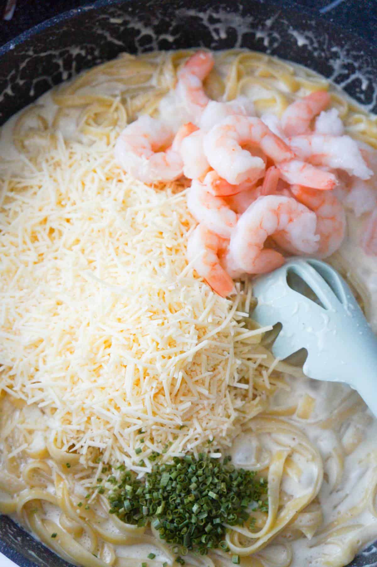 shredded parmesan cheese, chopped chives and cooked shrimp on top of fettuccine alfredo