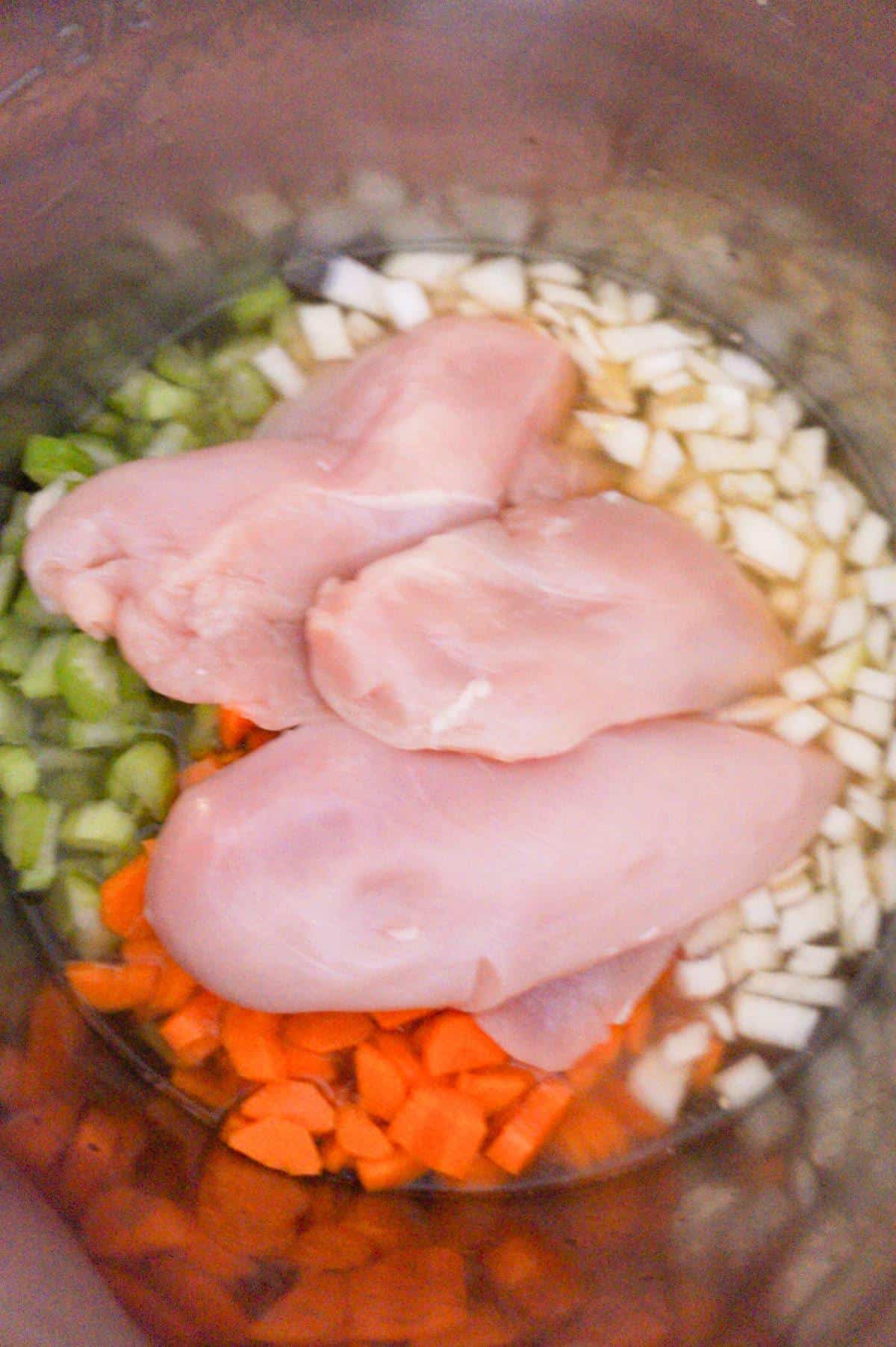 raw chicken breasts on top of veggies in an Instant Pot