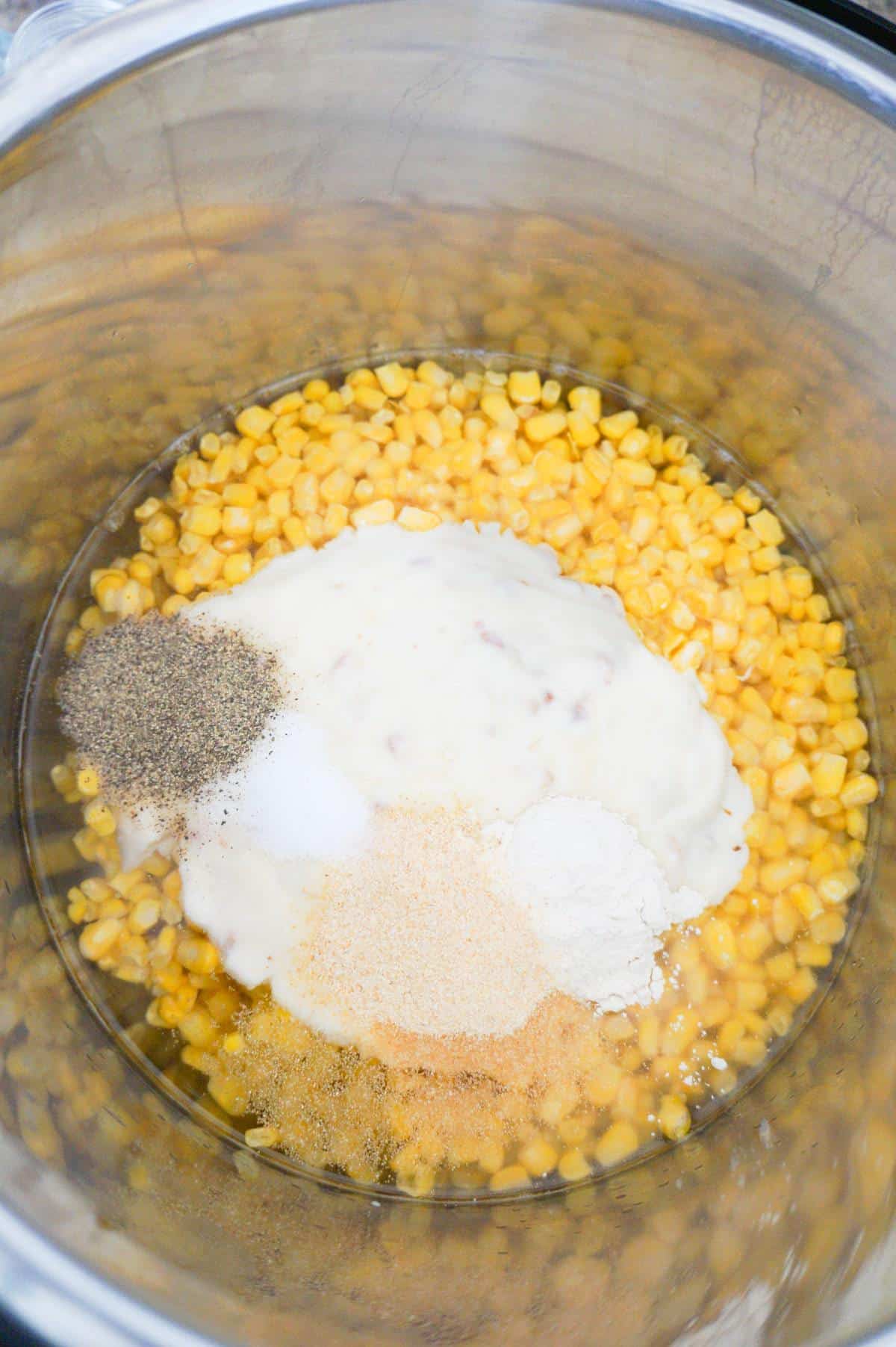 cream of bacon soup and spices on top of frozen corn in an Instant Pot