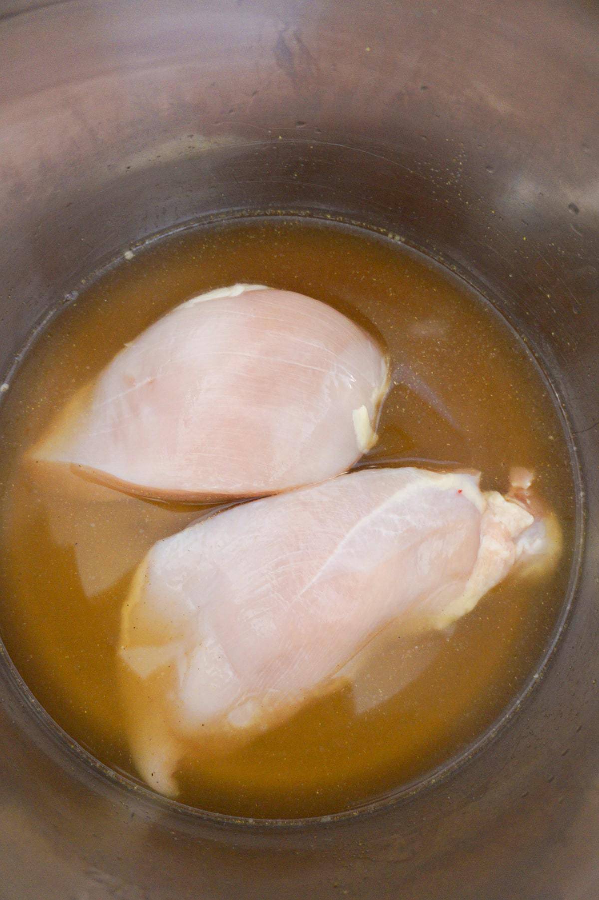 raw chicken breasts and chicken broth in an Instant Pot