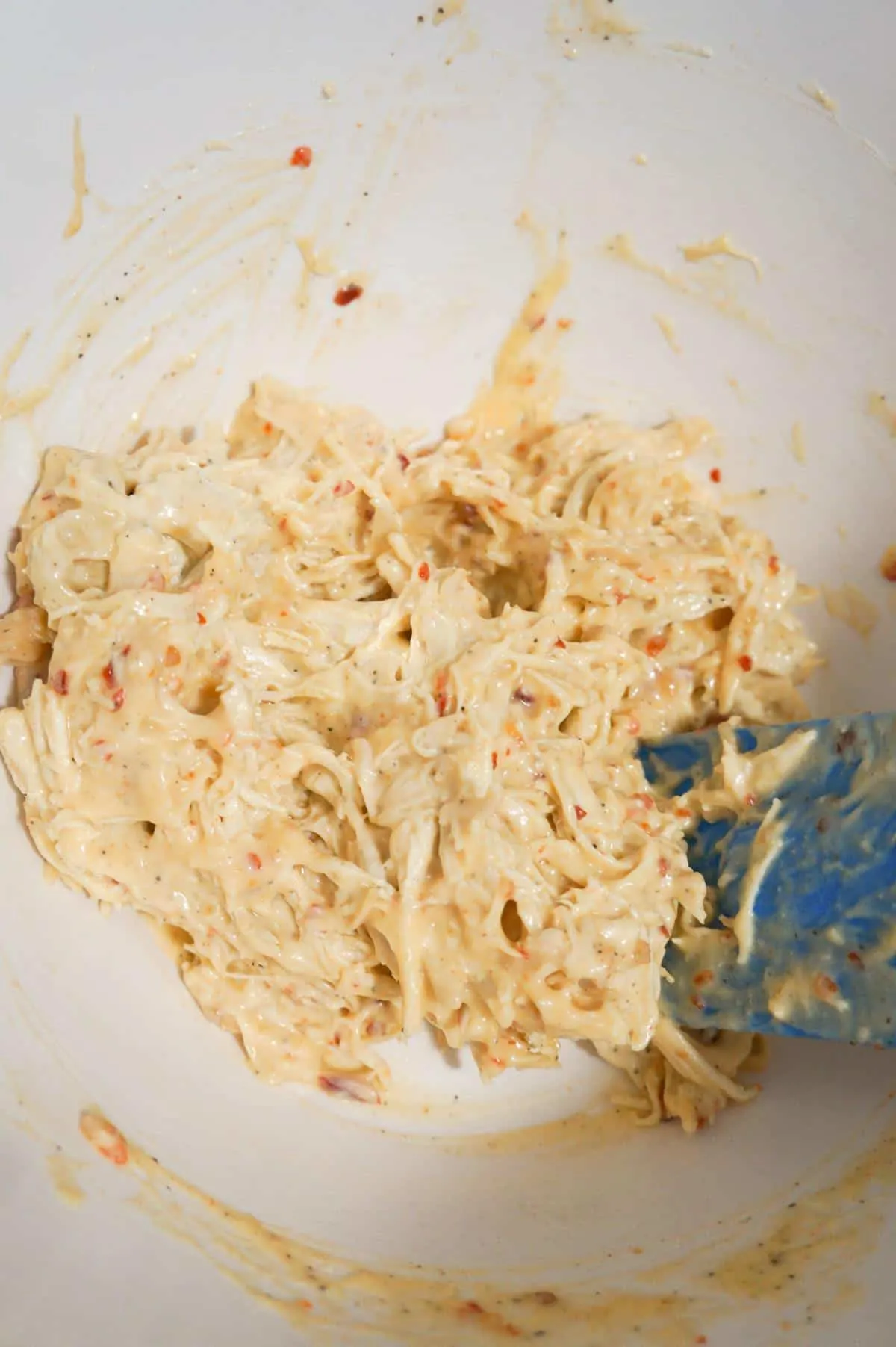 shredded chicken tossed in mayo and sweet chili sauce in a mixing bowl