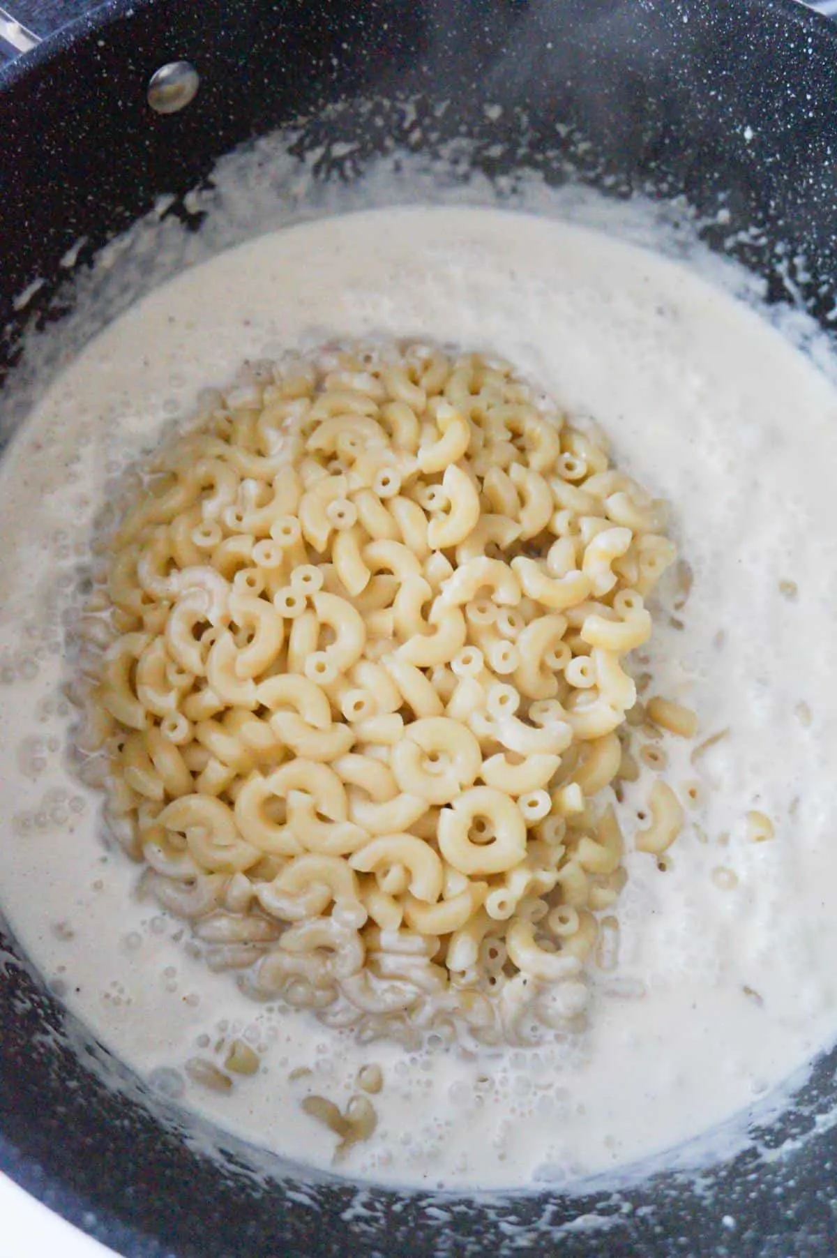 cooked macaroni on top of creamy sauce in a large pot