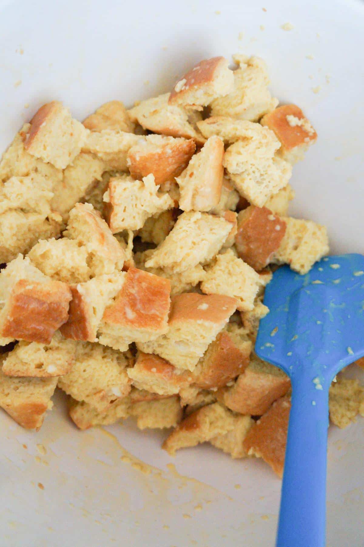 cubed bread coated in egg mixture in a mixing bowl