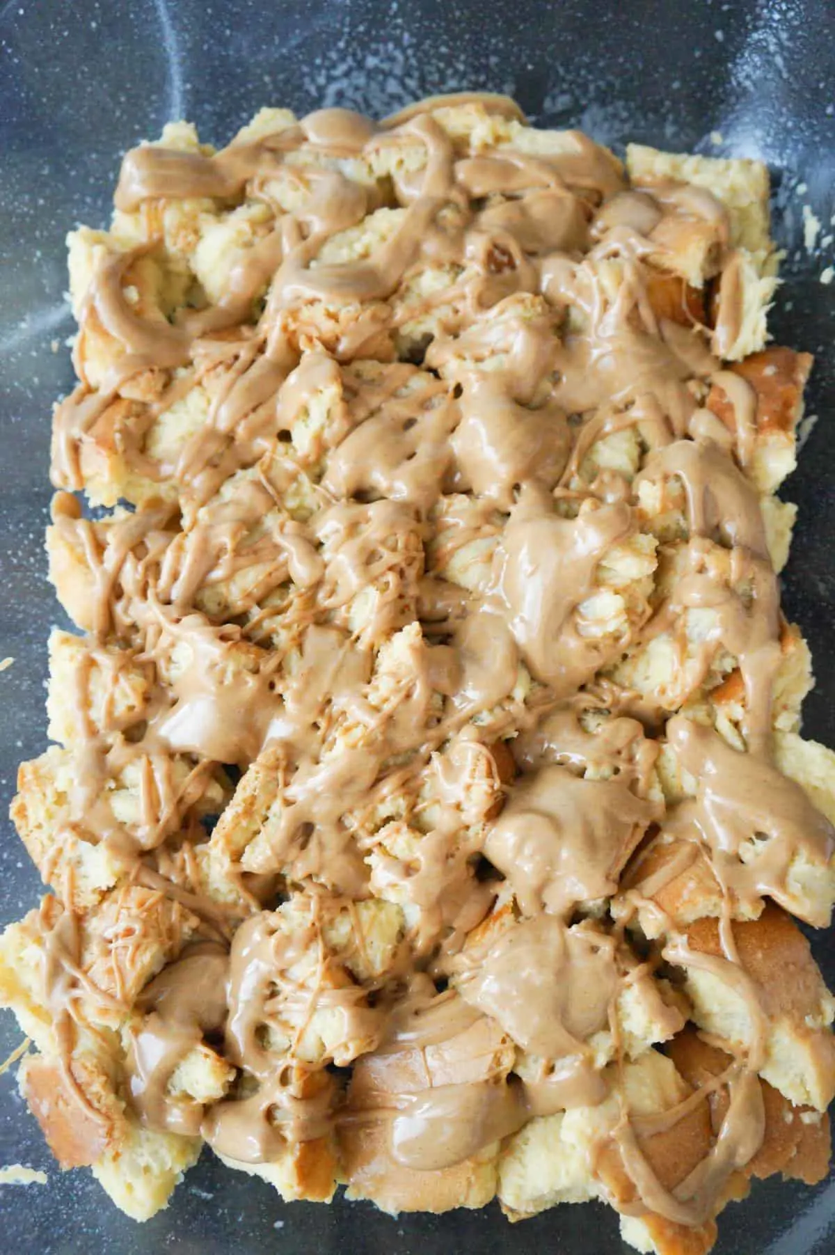 peanut butter drizzled over cubed bread in a baking dish