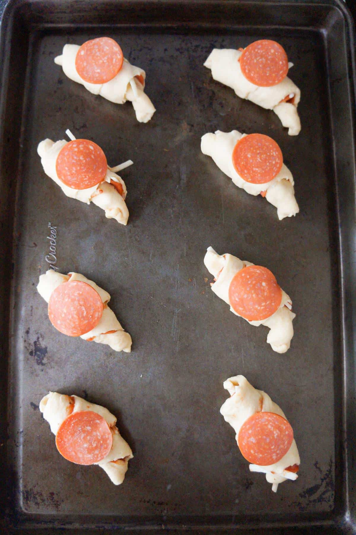 pepperoni slices on top of crescent rolls before baking
