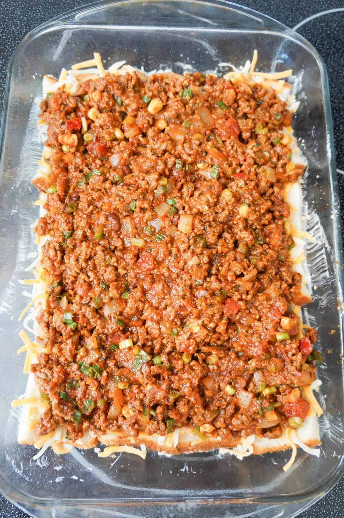 taco ground beef mixture on top fo bread in a baking dish