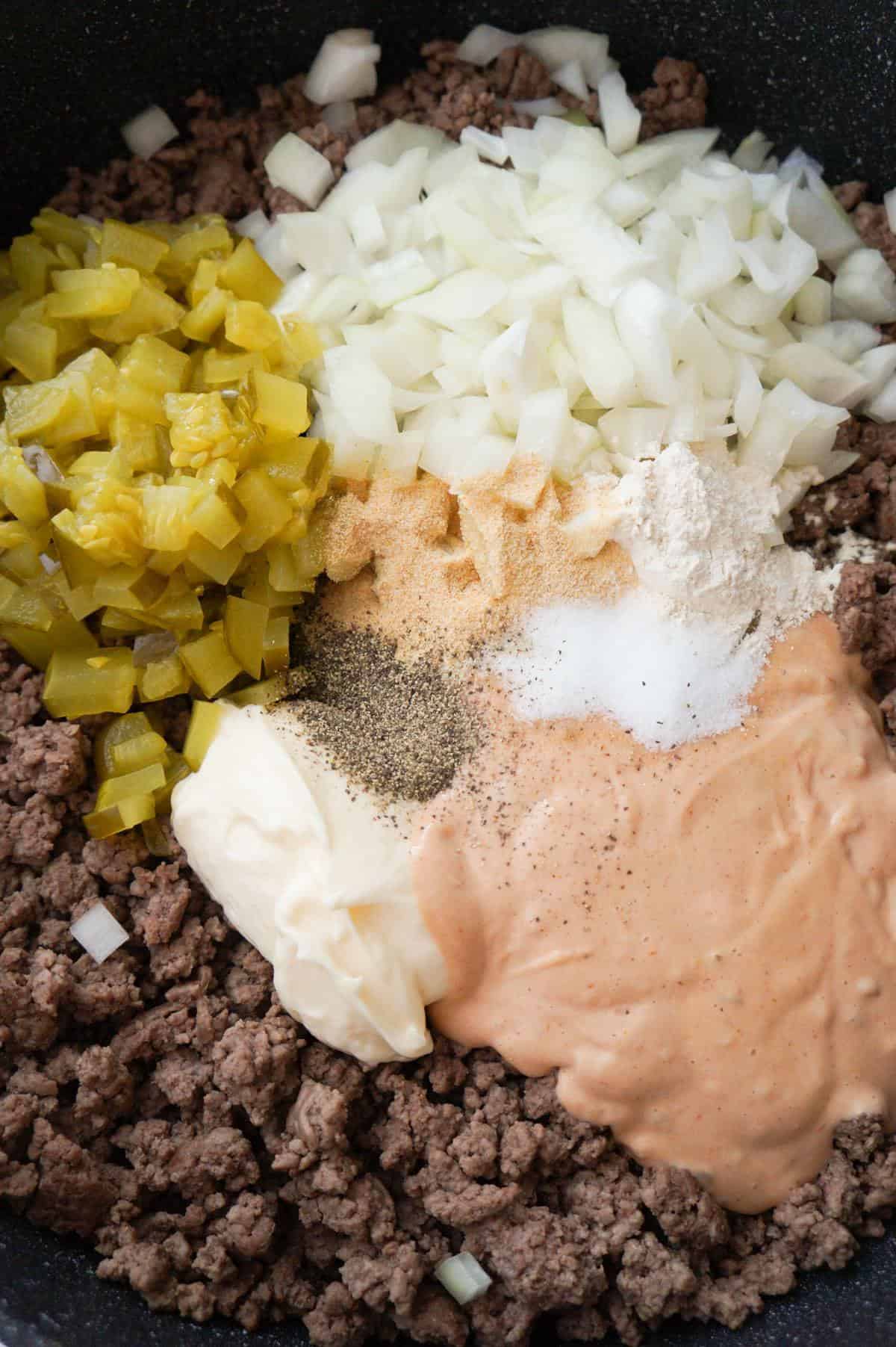 diced dill pickles, diced onions, Thousand Island dressing, mayo and spices on top of cooked ground beef in a saute pan