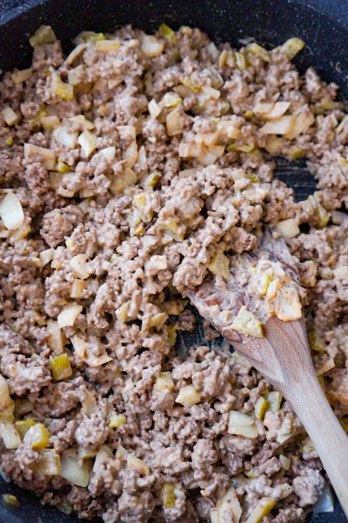 ground beef, onions, and pickles tossed in sauce in a saute pan