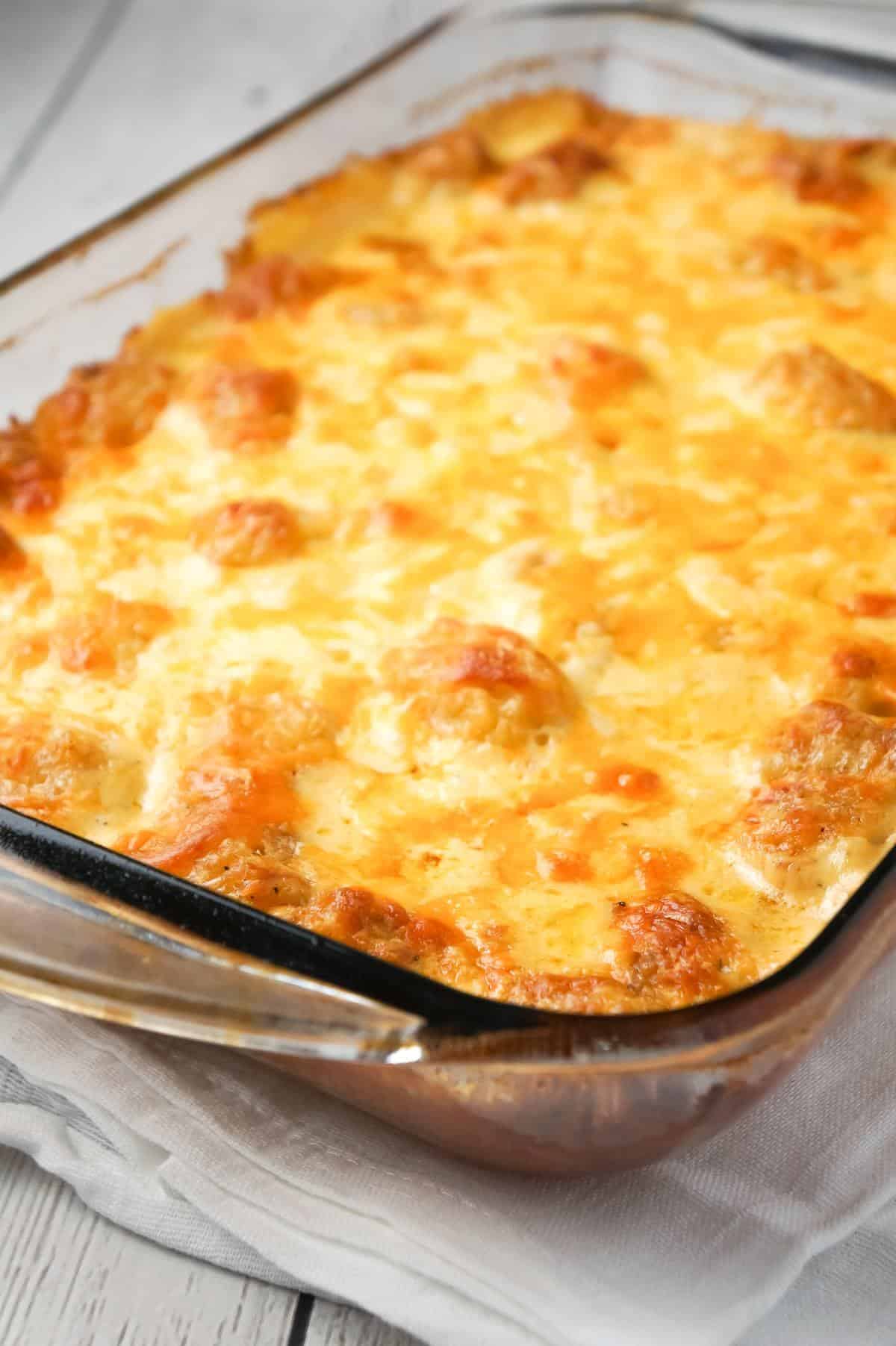 Cheesy Garlic Tater Tot Casserole is an easy potato side dish recipe using heavy cream, cheddar cheese soup, frozen tater tots, garlic puree and shredded mozzarella, cheddar and Parmesan cheese.