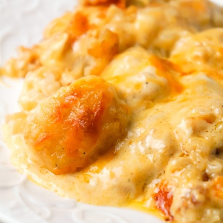 Cheesy Garlic Tater Tot Casserole is an easy potato side dish recipe using heavy cream, cheddar cheese soup, frozen tater tots, garlic puree and shredded mozzarella, cheddar and Parmesan cheese.