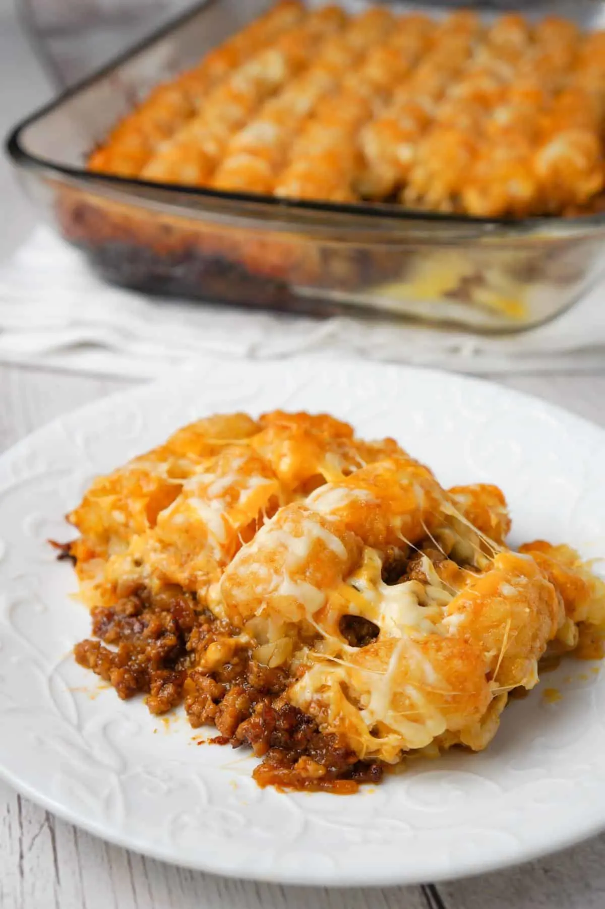 Dr Pepper Pork Tater Tot Casserole is a hearty dish with a base of ground pork cooked in Dr Pepper and BBQ sauce and topped with tater tops and shredded cheese.