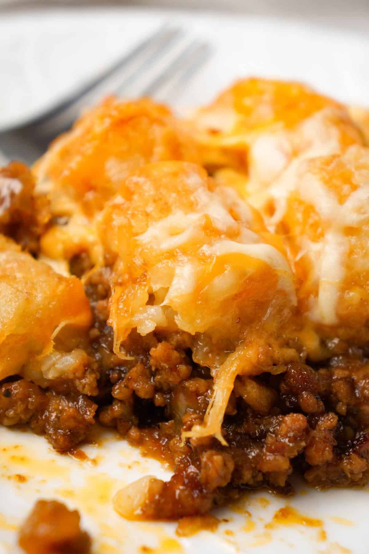 Dr Pepper Pork Tater Tot Casserole is a hearty dish with a base of ground pork cooked in Dr Pepper and BBQ sauce and topped with tater tops and shredded cheese.