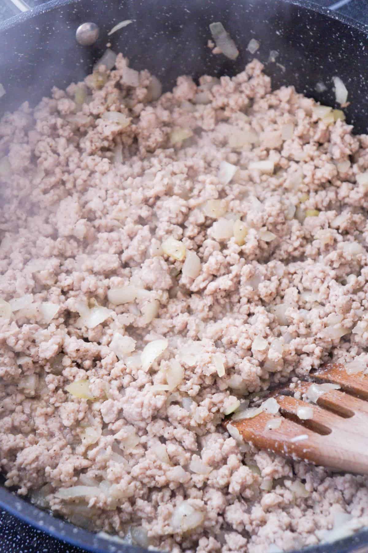 cooked ground pork and diced onions in a saute pan
