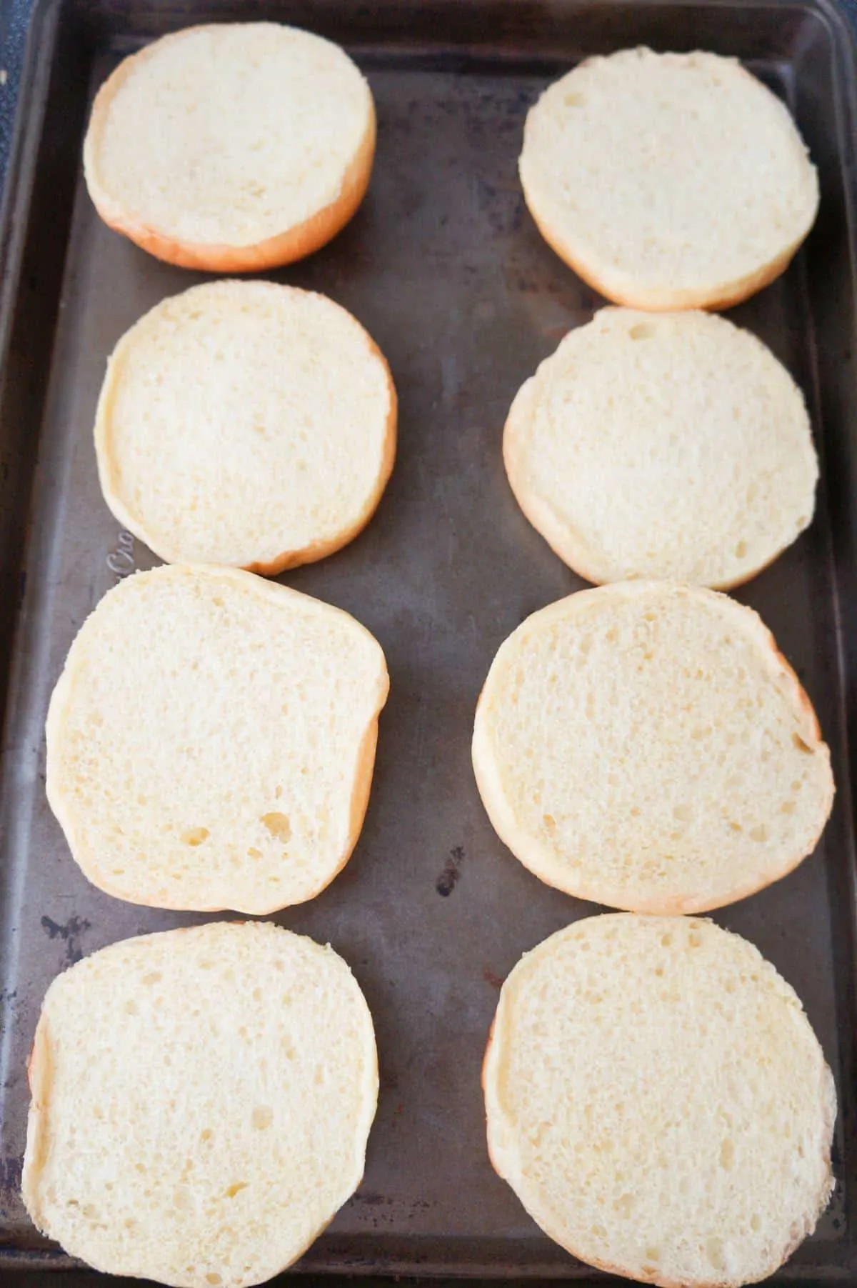 brioche buns in a single layer on a baking sheet