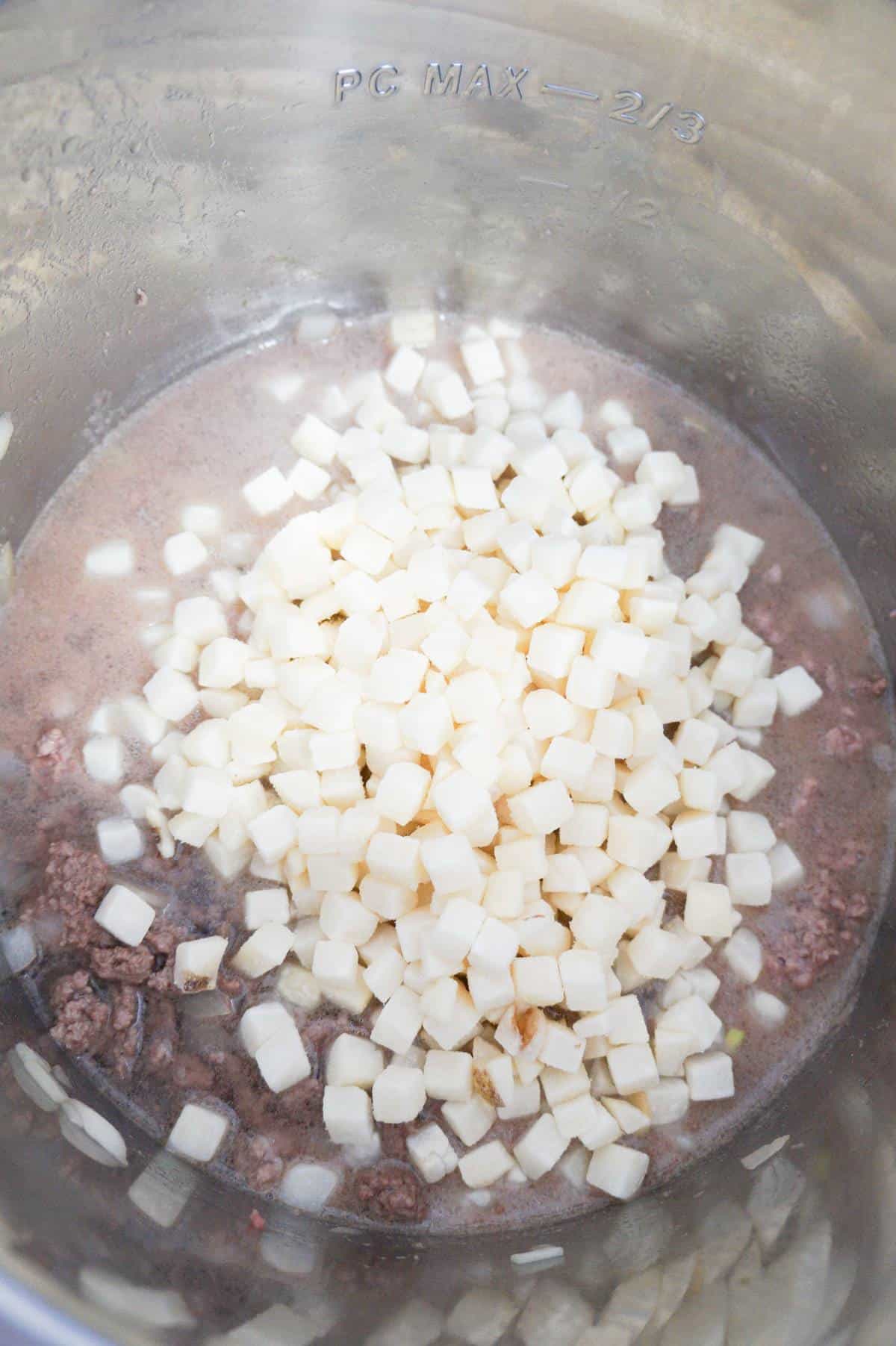 frozen diced hash brown potatoes on top of ground beef and water in an Instant Pot