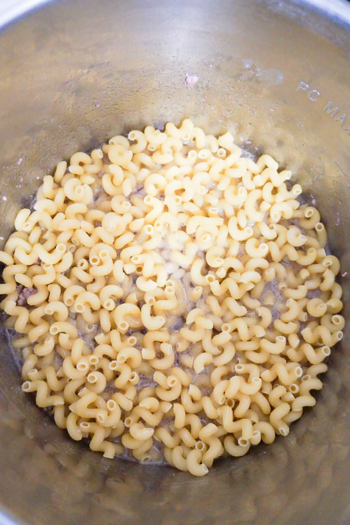 cavatappi noodles on top of ground beef in an Instant Pot