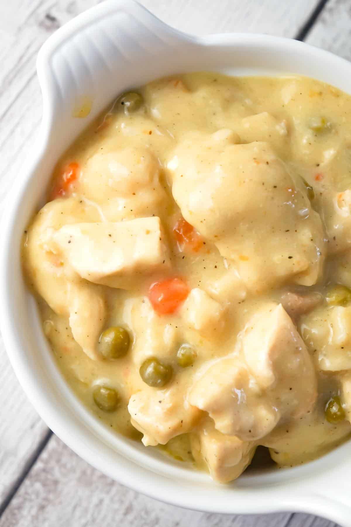 Instant Pot Chicken and Dumplings with Biscuits is an easy dump and start recipe using boneless, skinless chicken breasts, cream of chicken soup, Pillsbury refrigerated biscuits and canned peas and carrots.