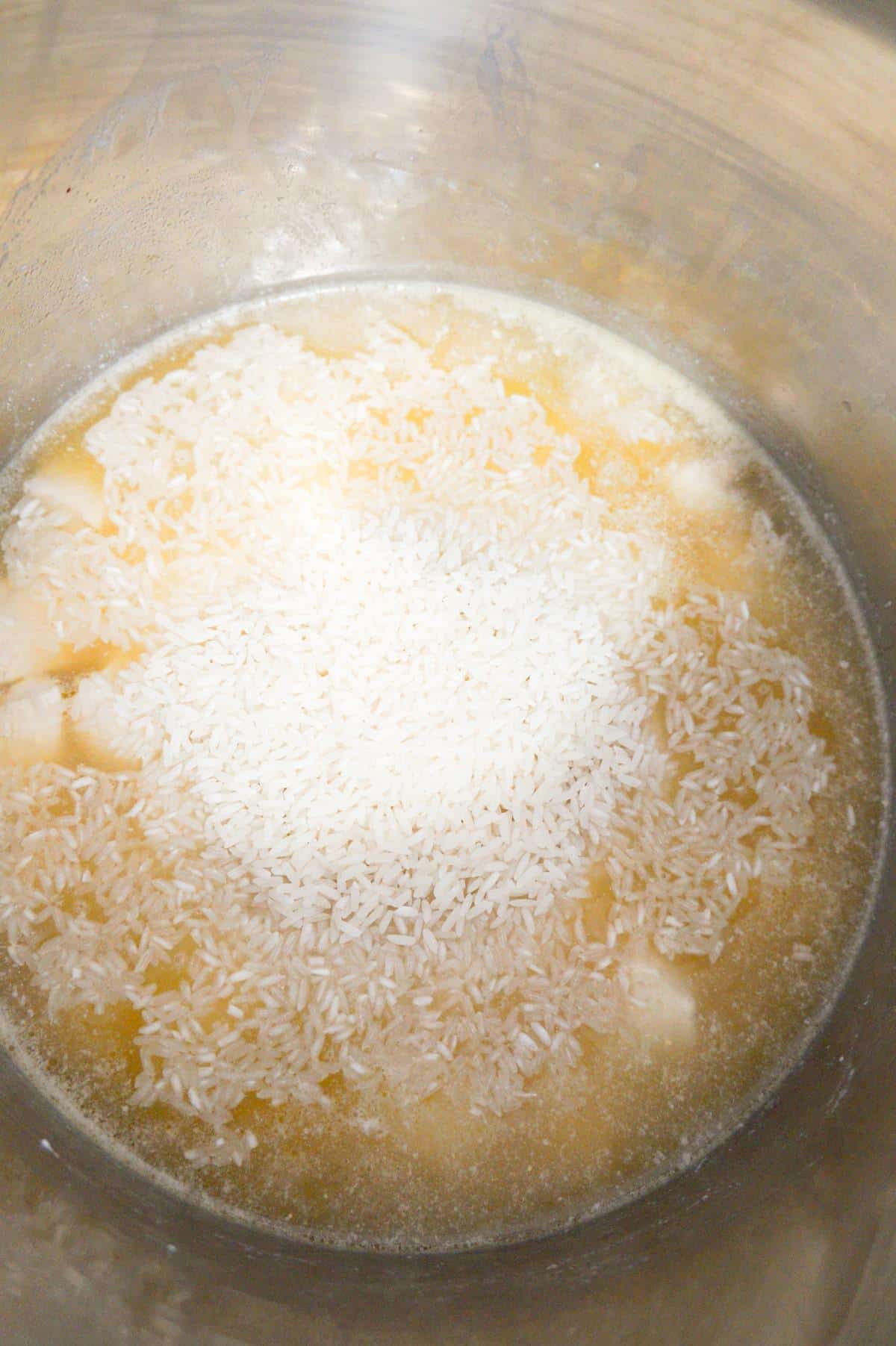 long grain white rice on top of chicken and broth in an Instant Pot