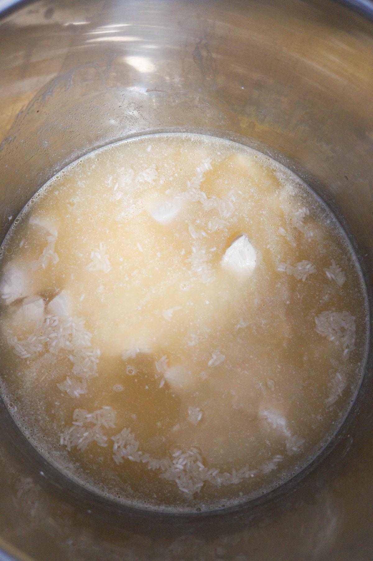 chicken breast chunks and rice submerged in broth in an Instant Pot