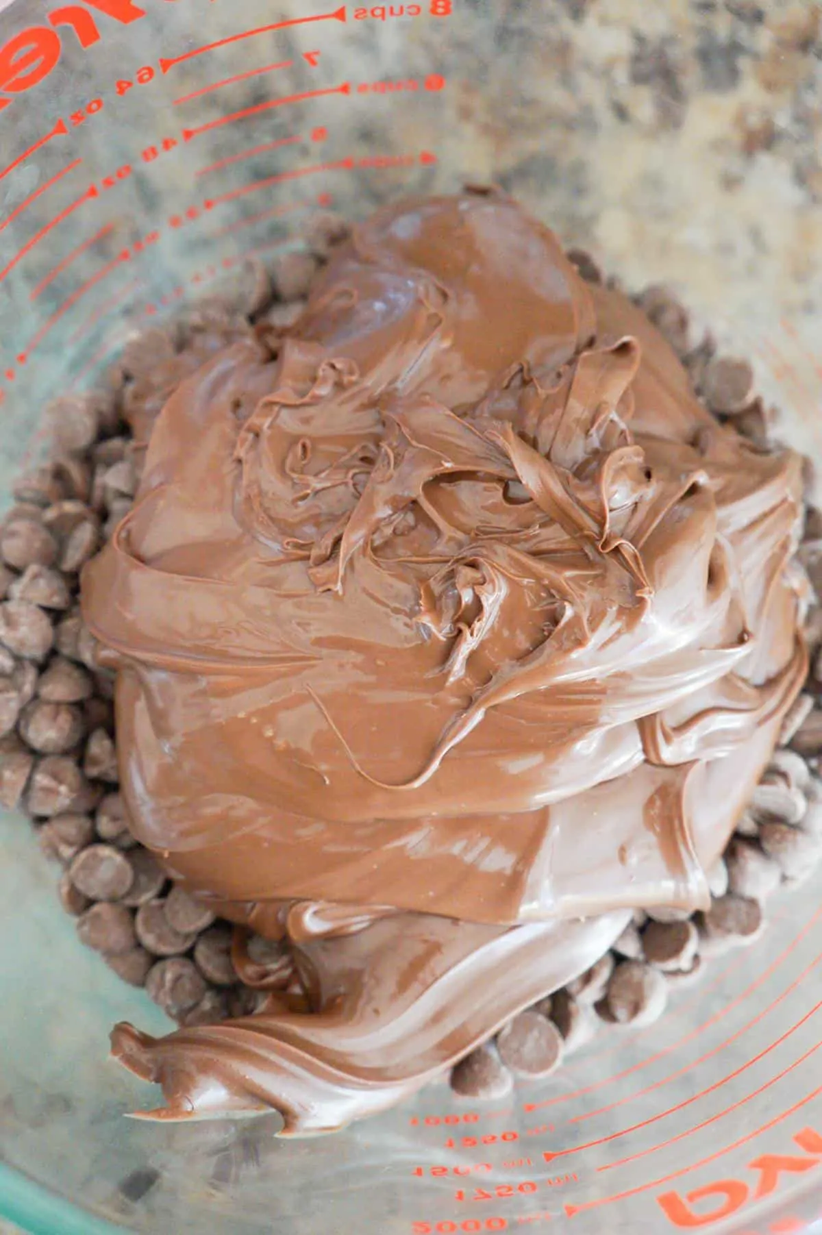 Nutella on top of milk chocolate chips in a mixing bowl