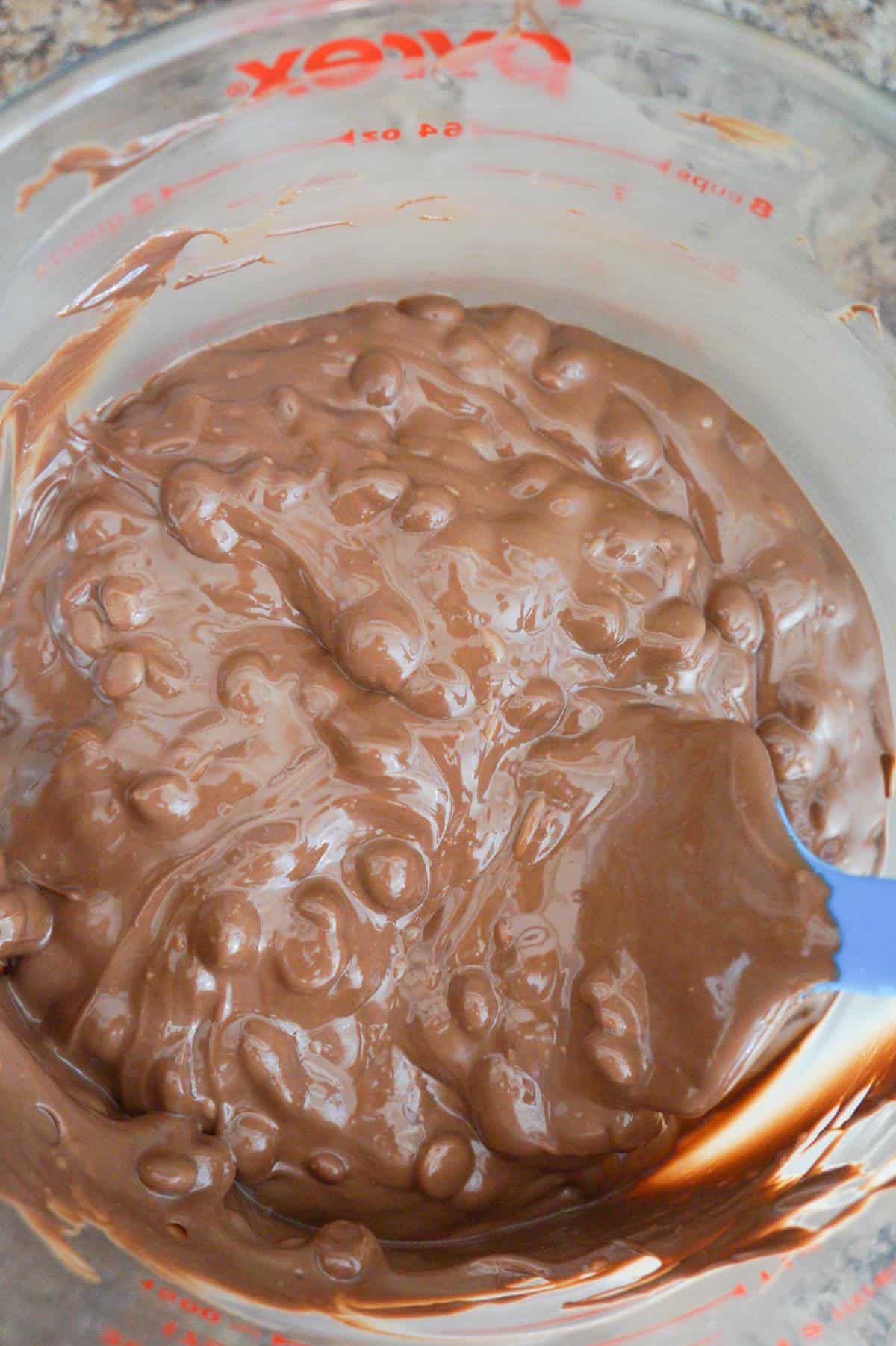 milk chocolate chips and Nutella being stirred together in a glass bowl