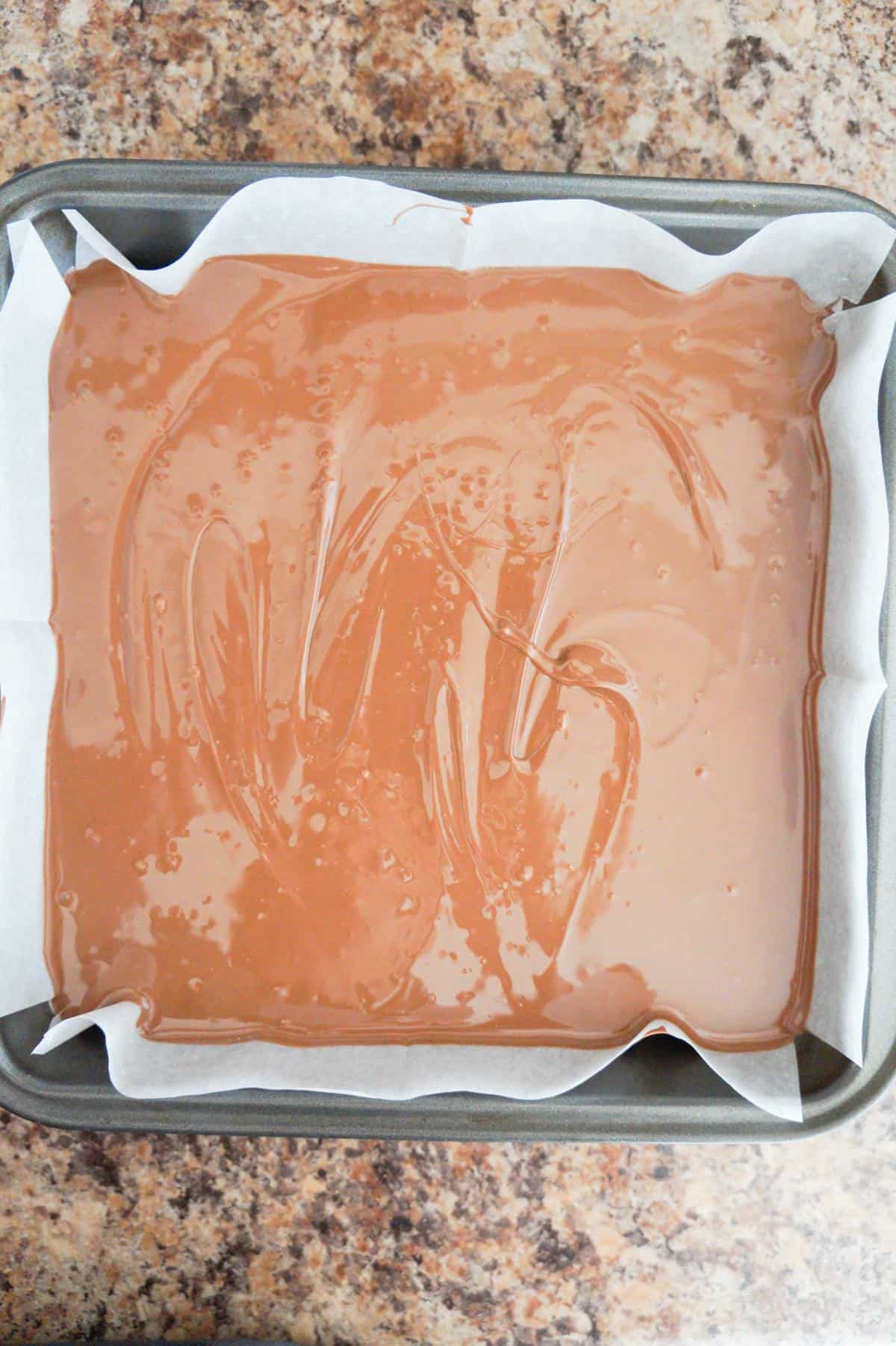 melted Nutella and milk chocolate mixture in a parchment lined baking pan