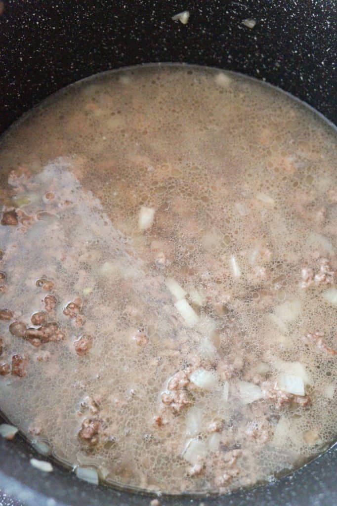 water and cooked ground beef in a pot