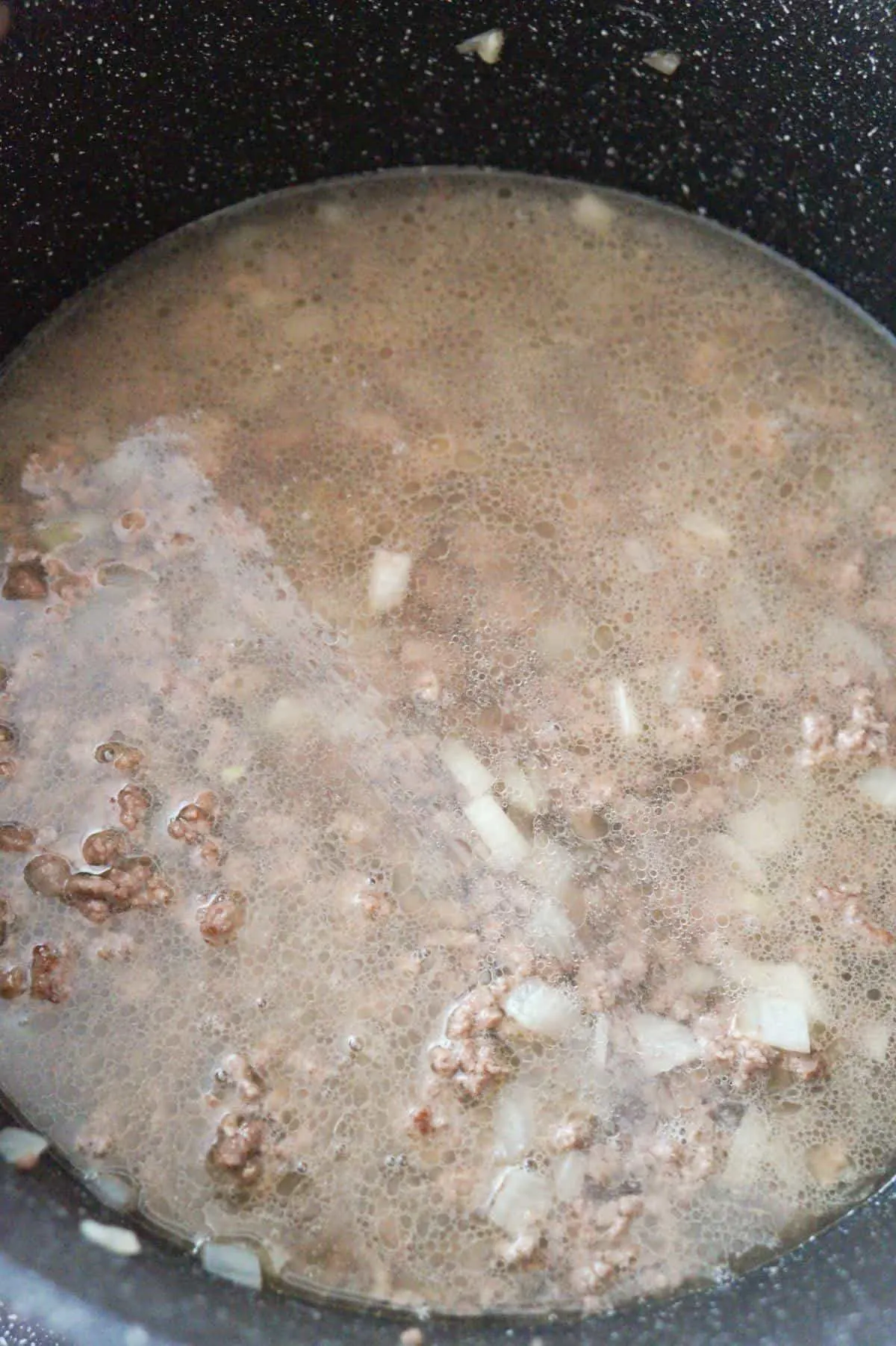 water and cooked ground beef in a pot