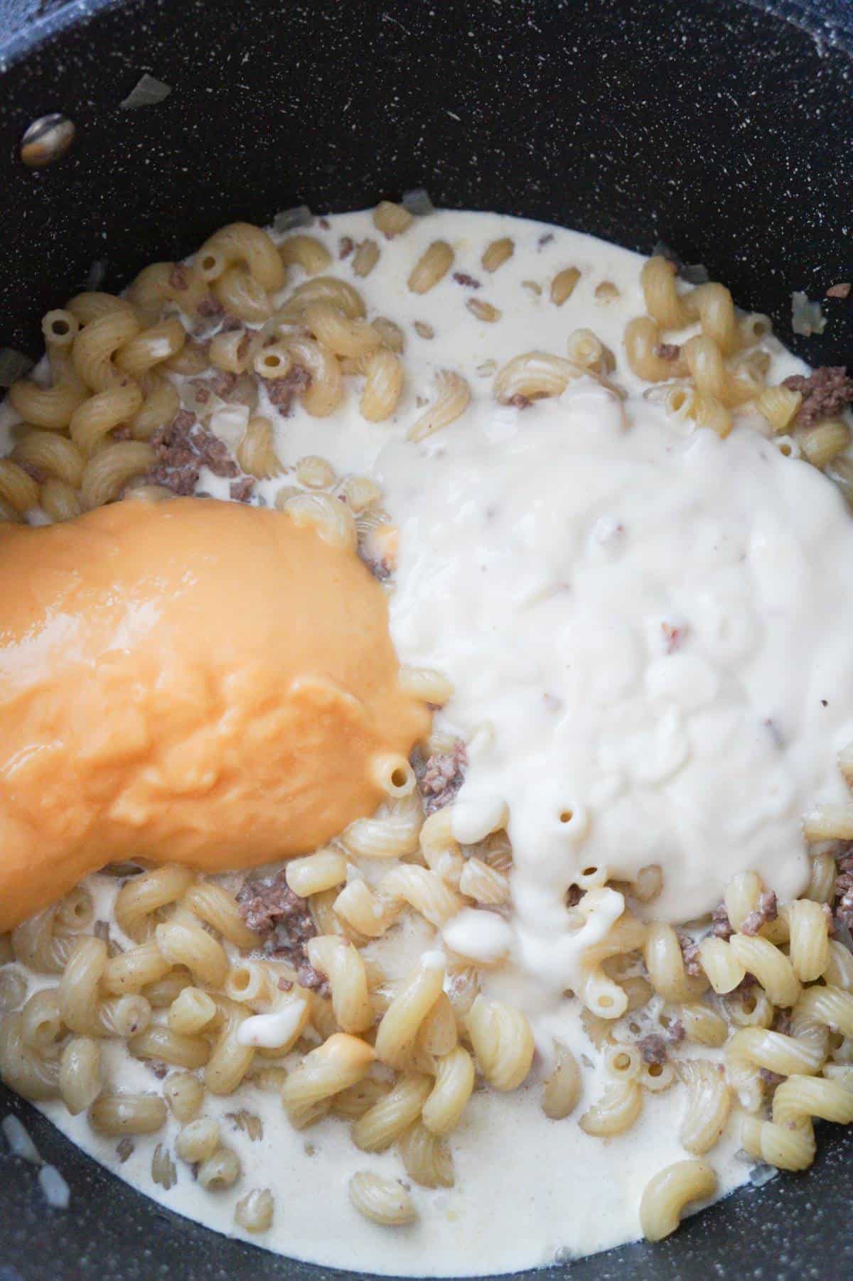 cheese soup and bacon soup on top of ground beef and noodles in a pot