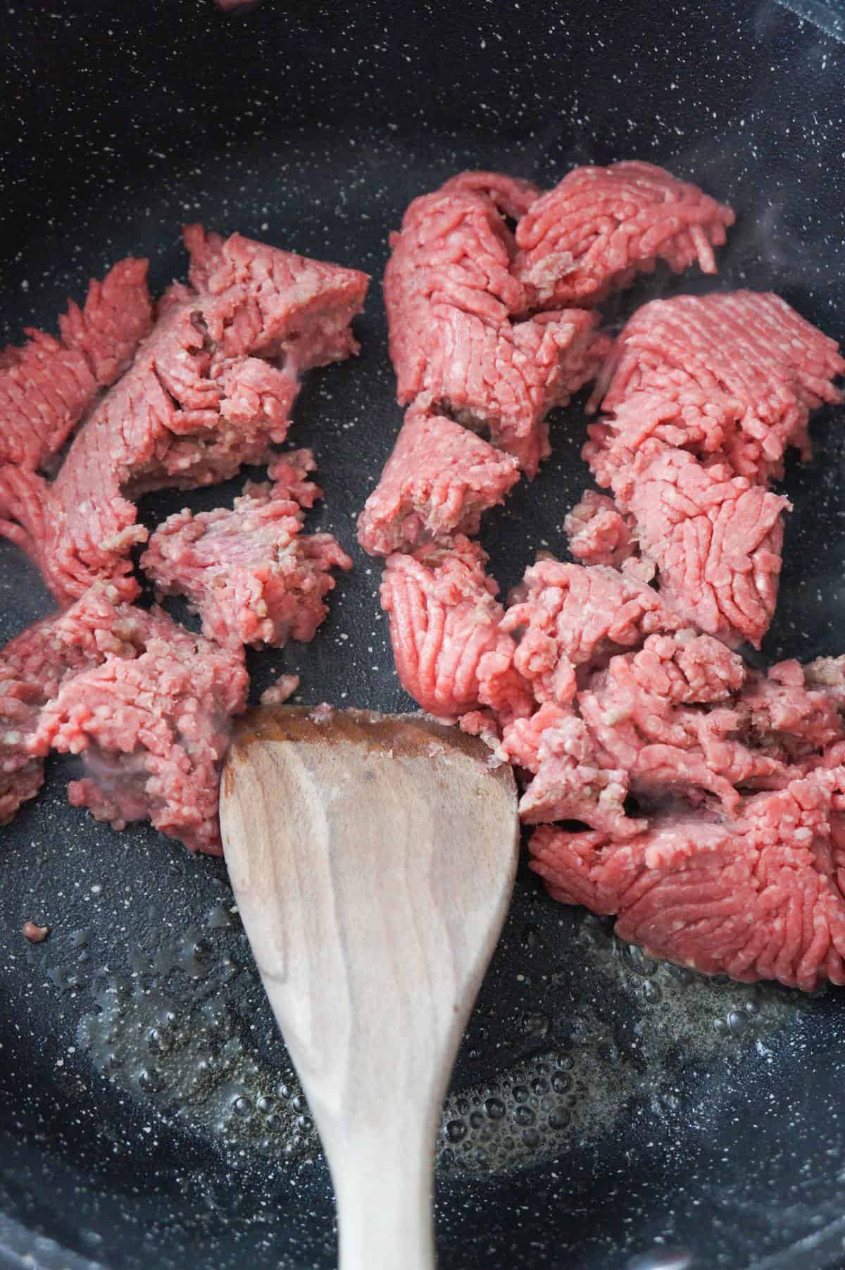 raw ground beef in a saute pan.