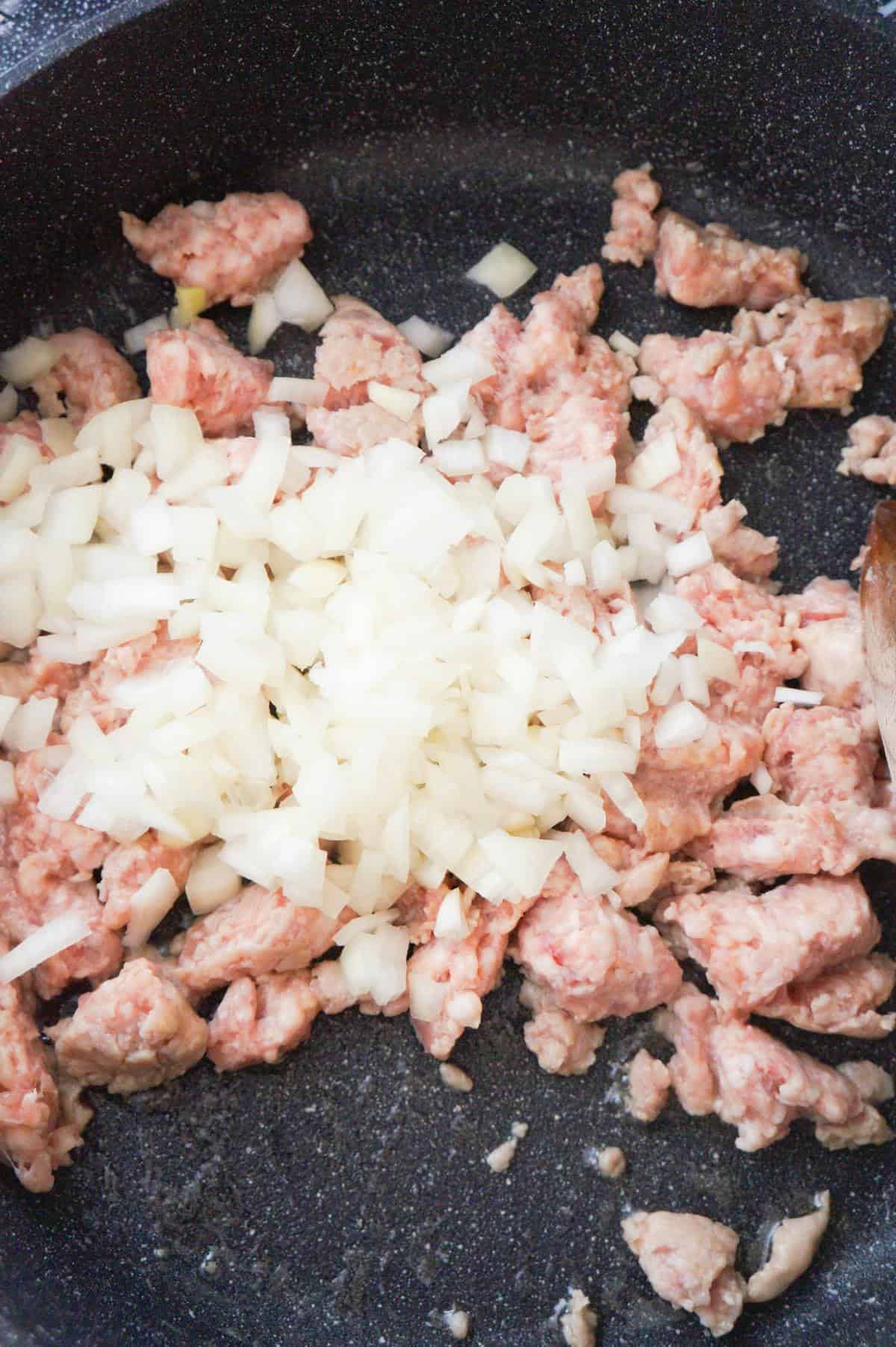 diced onions on top of sausage meat in a saute pan