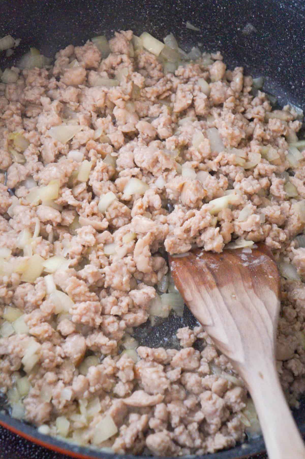 ground sausage meat and diced onions cooking in a saute pan