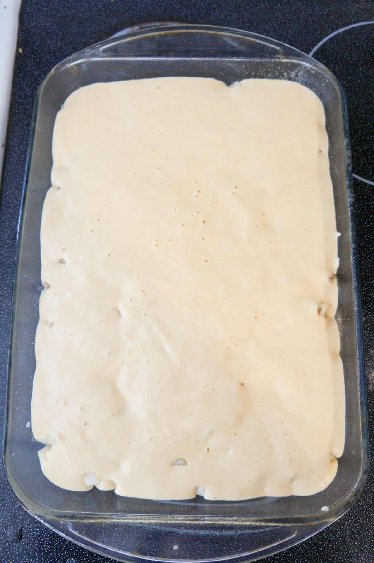 pancake batter on top of breakfast casserole in a baking dish