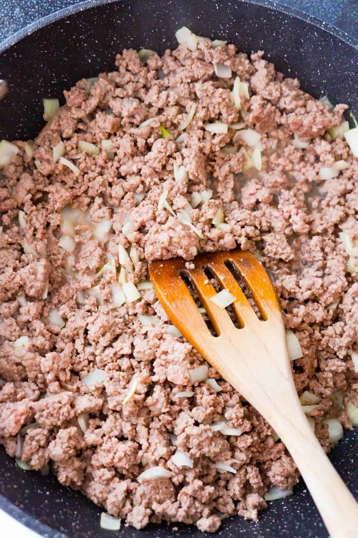 ground beef and diced onions in a saute pan