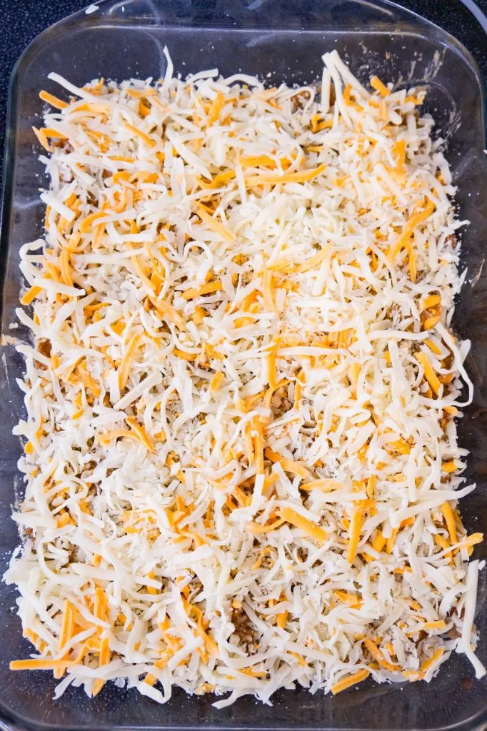 shredded cheese on top of ground beef mixture in a baking dish
