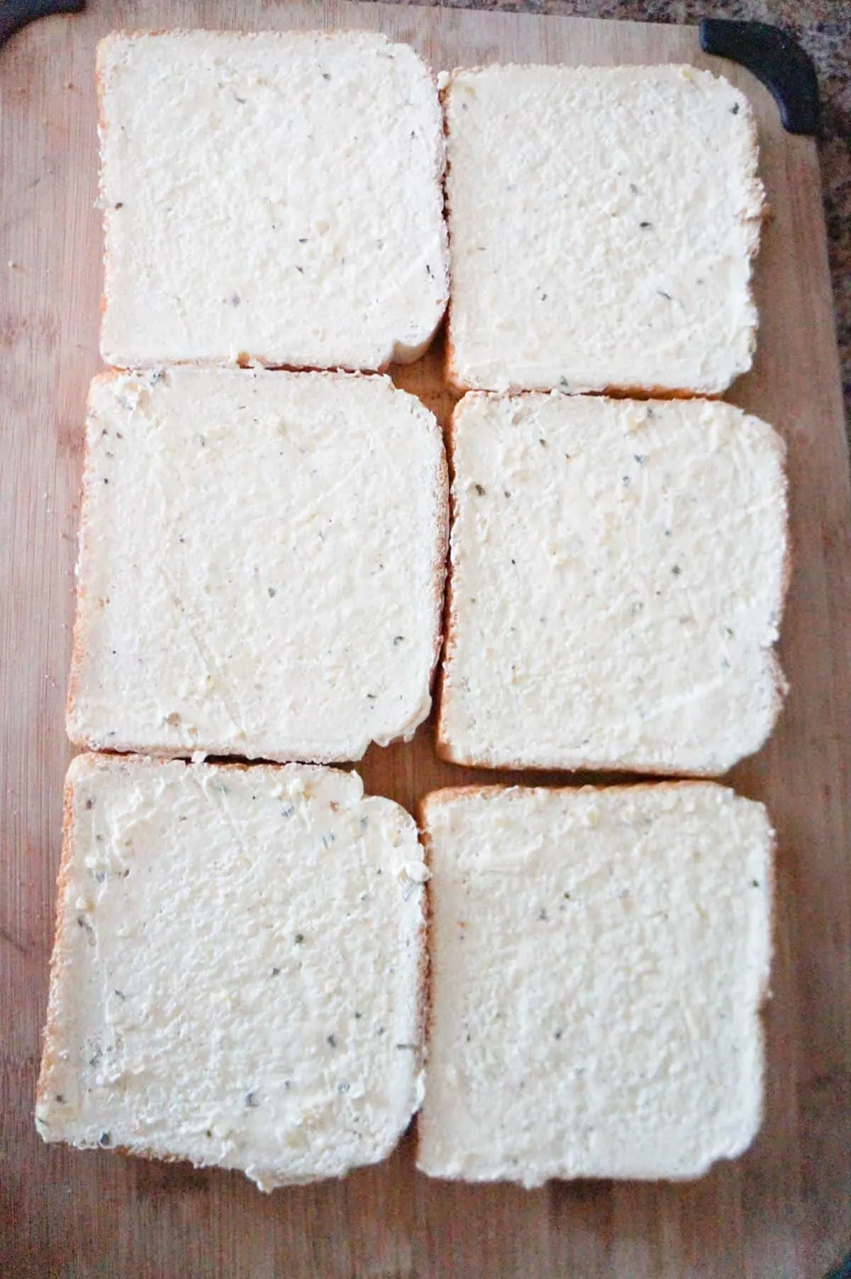 slices of bread spread with garlic margarine on a cutting board