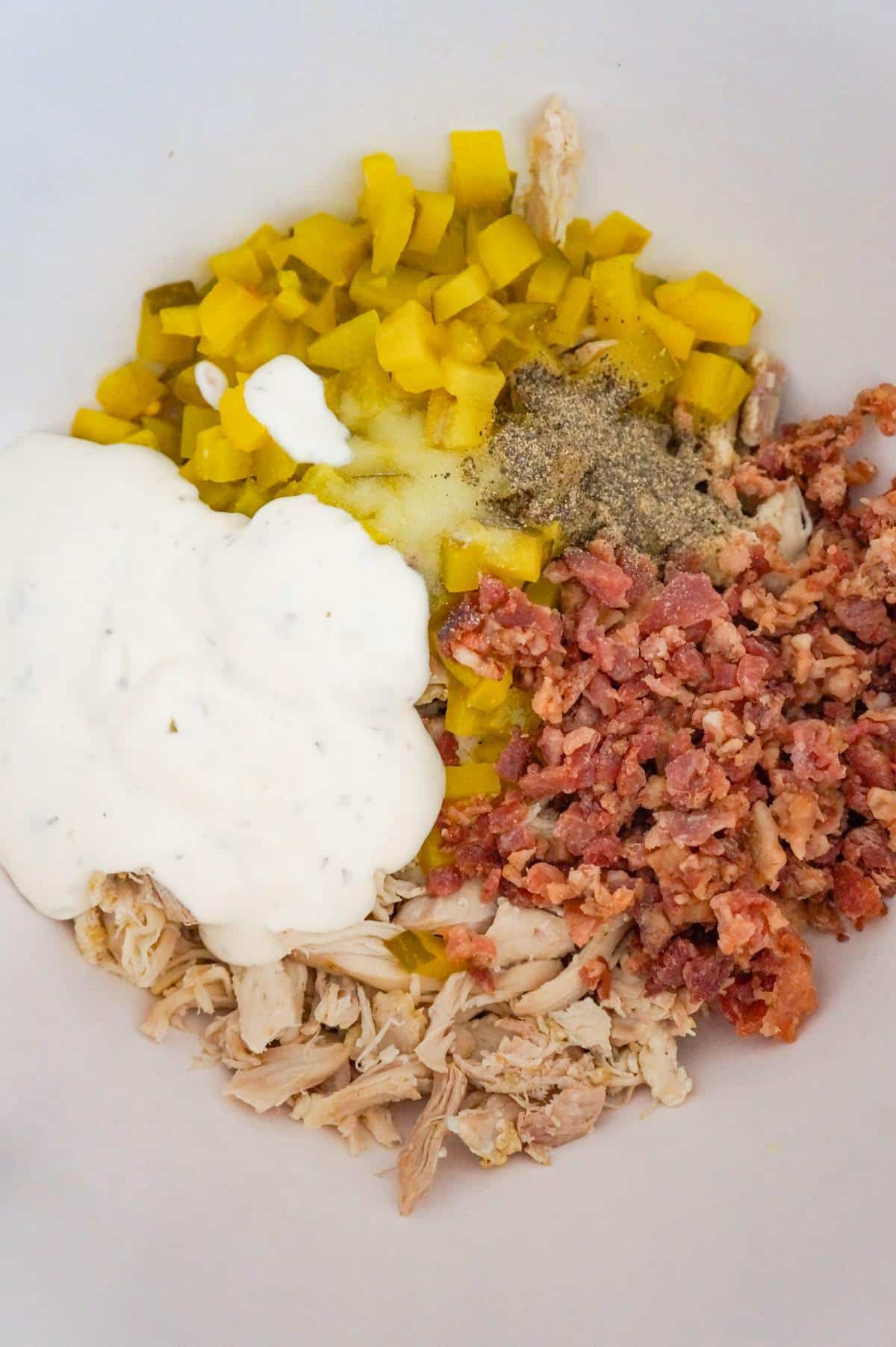 ranch dressing, shredded chicken, diced dill pickles and crumbled bacon in a mixing bowl