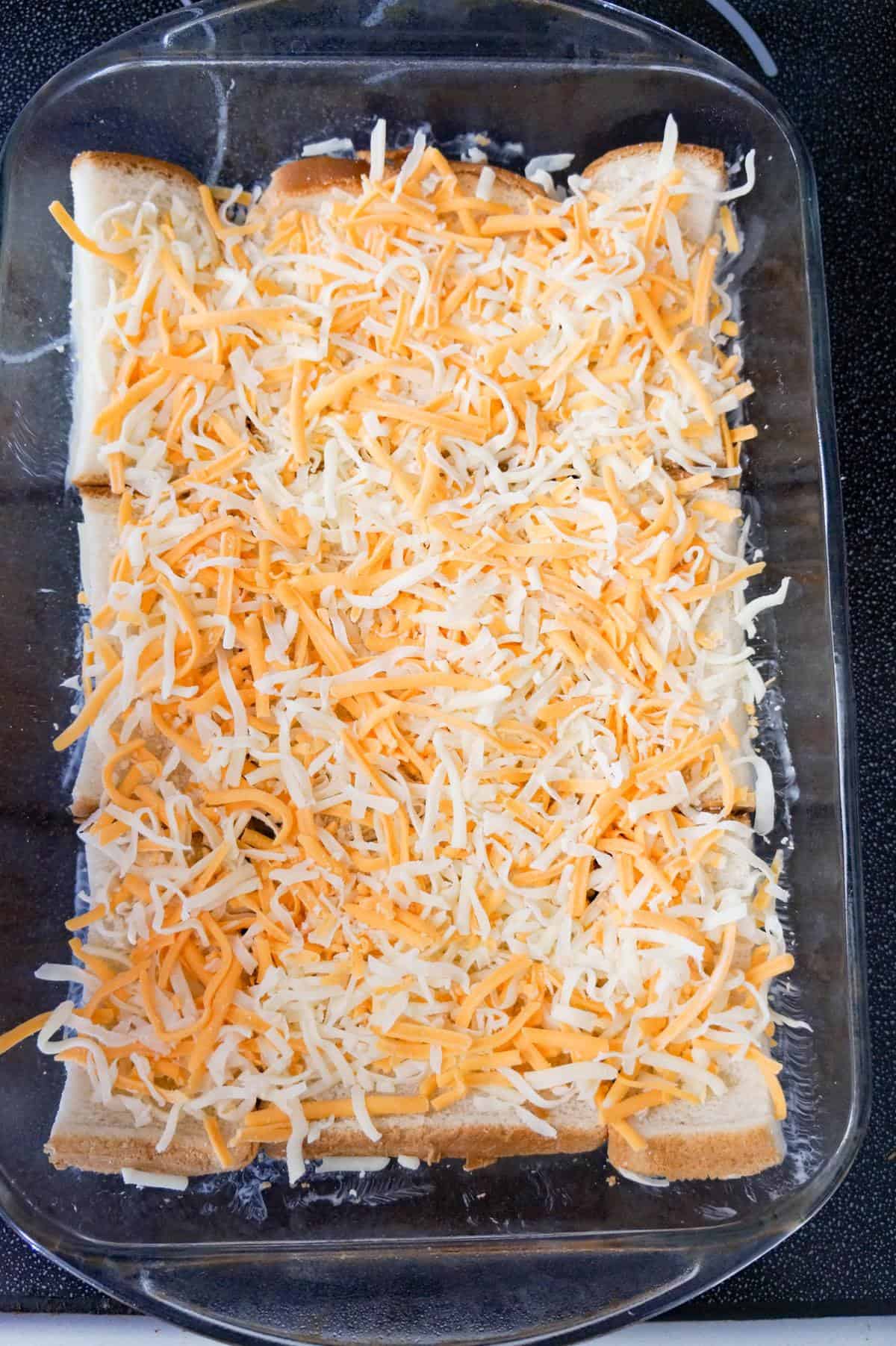 shredded cheese on top of bread in a baking dish