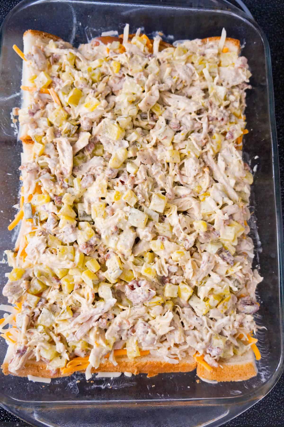 dill pickle chicken mixture on top of bread in a baking dish